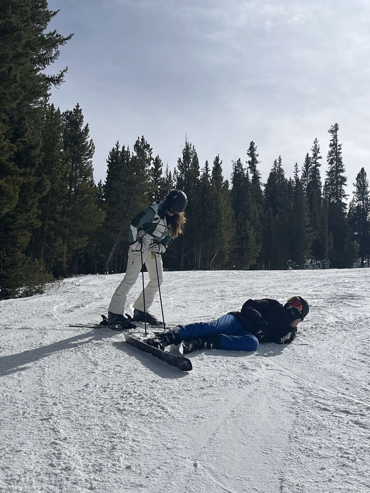 A snowboarder down on the slope as Ruby skis past